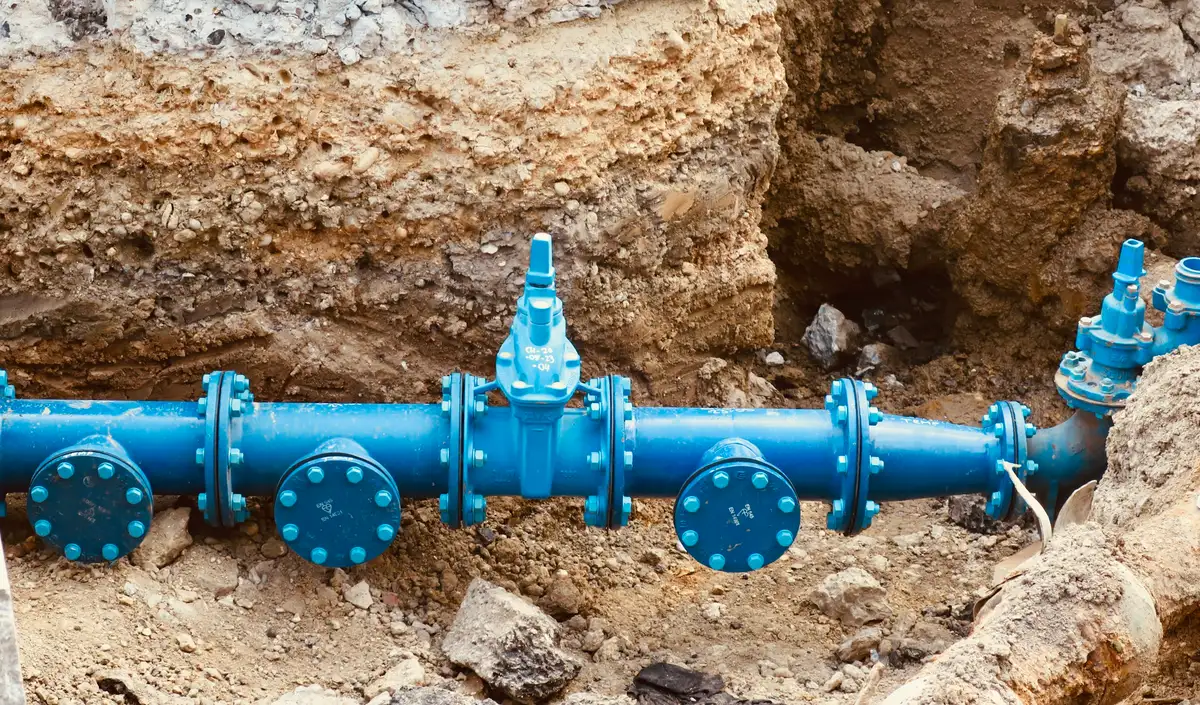 Blue water pipework and valves laid in an open trench