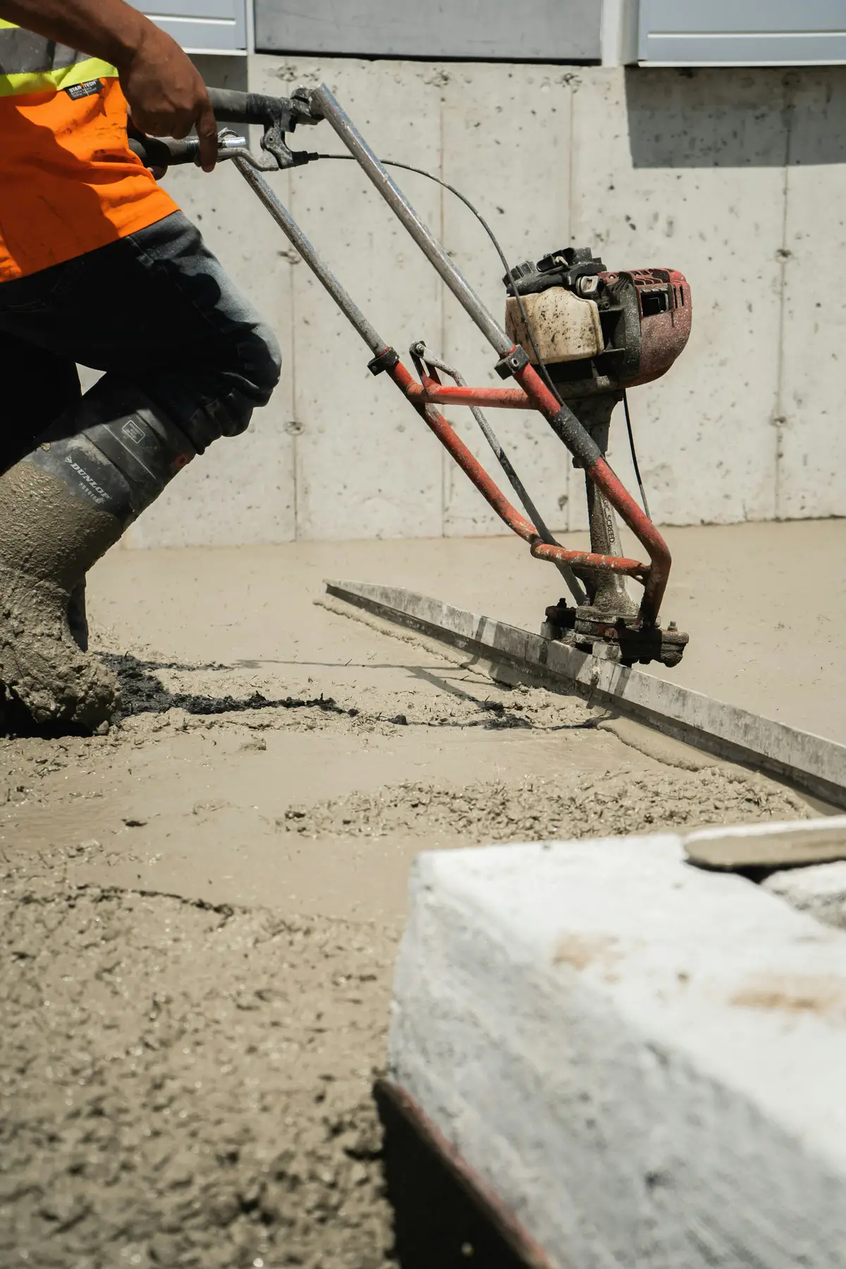 A groundworker levelling fresh concrete with a power screed